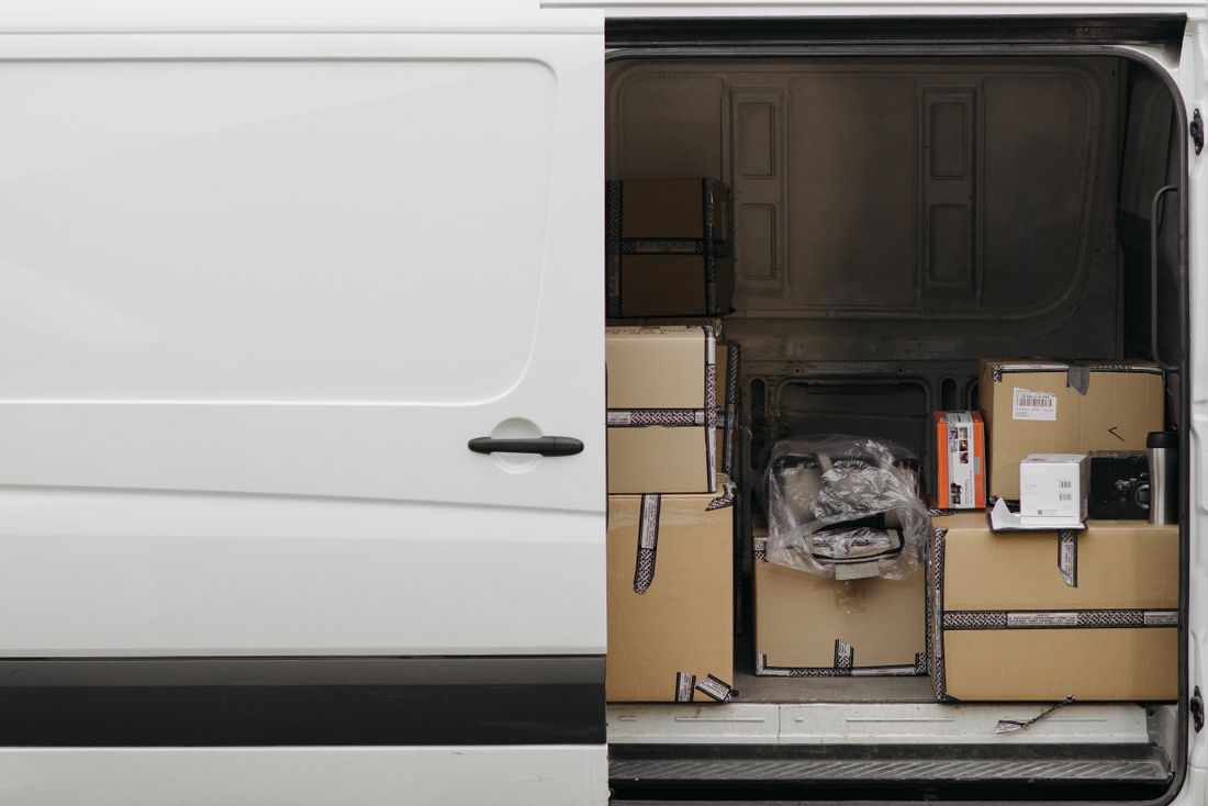 The open back doors of a cargo van packed with taped moving boxes, no people visible.