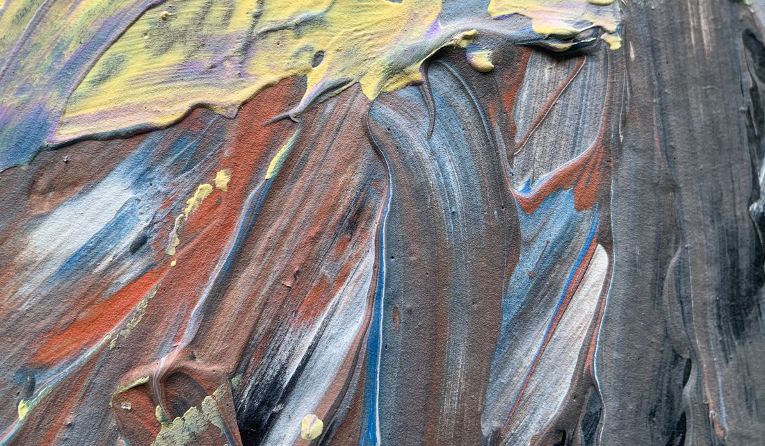 A close crop of thick acrylic paint texture in rust, gray, and blue, brush ridges catching directional light.
