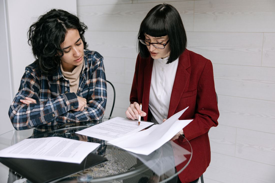 Two people at a table reviewing printed pages together, one pointing at a page