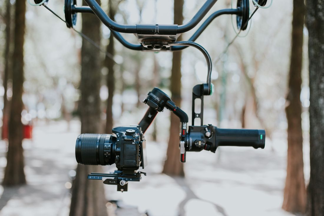 A camera mounted on a stabilizer rig hanging among bare winter trees, set up for a single video shoot