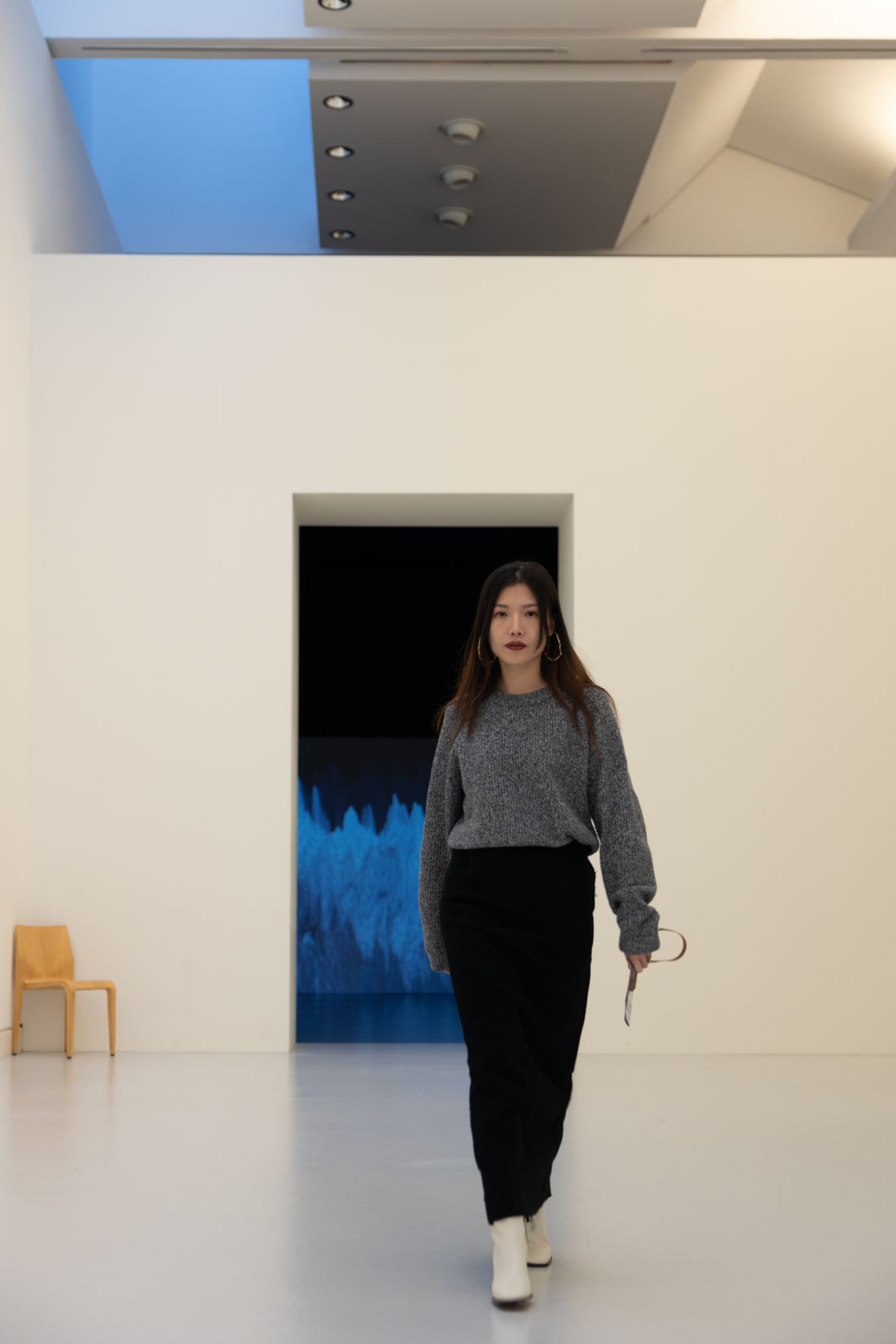 A person walking confidently through a minimalist, plain gallery space