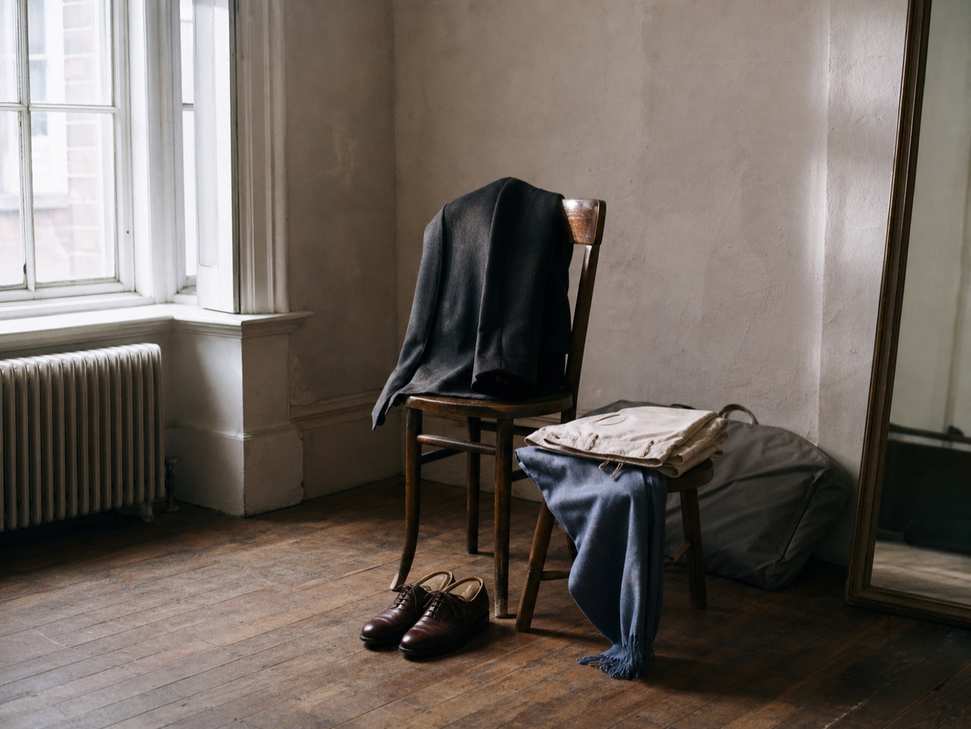 Concept image of a styled outfit prepared near a studio window with a chair, shoes, and garment bag
