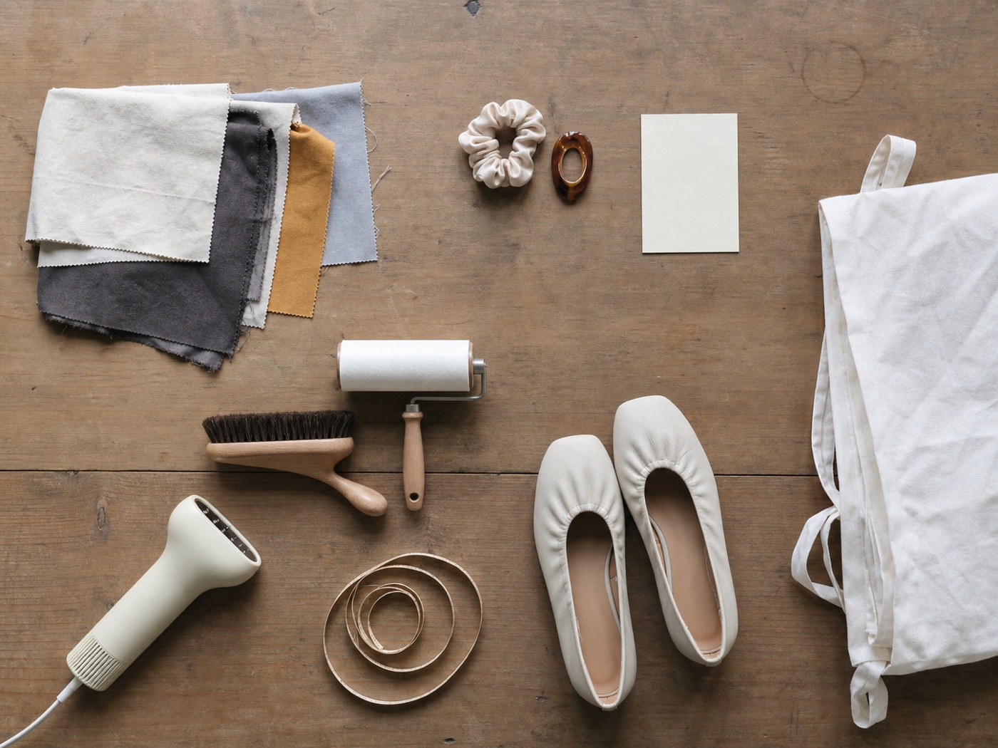Concept image of styling tools, fabric swatches, shoes, and accessories arranged on a wooden table