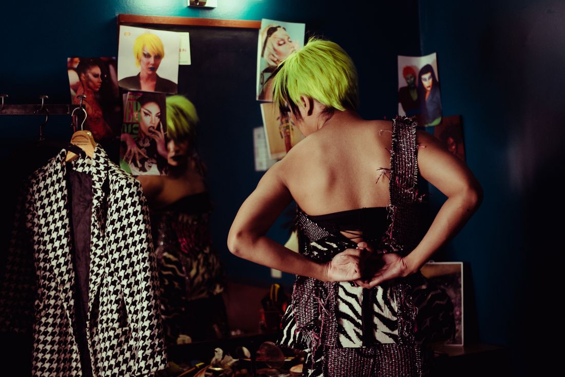 Back view of performer in bright wig reflecting in mirror while preparing in green room.