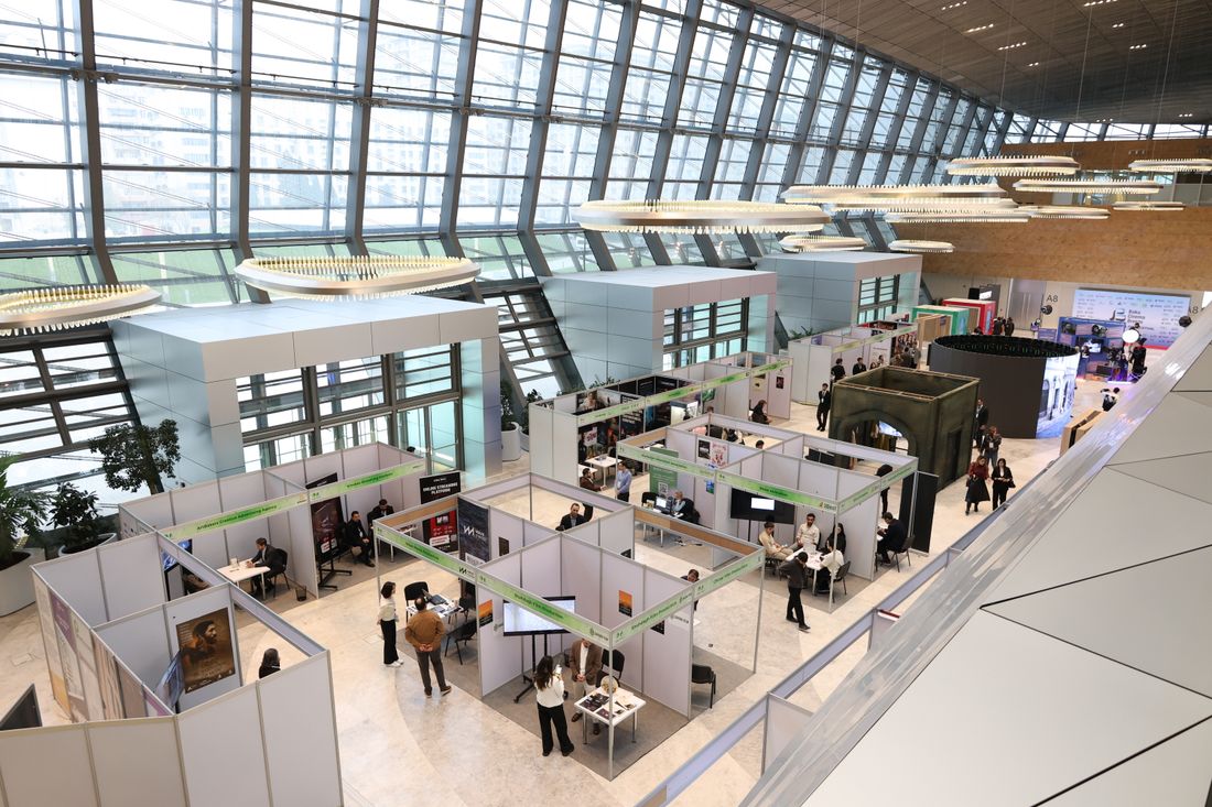 A bustling indoor exhibition hall with booths and attendees