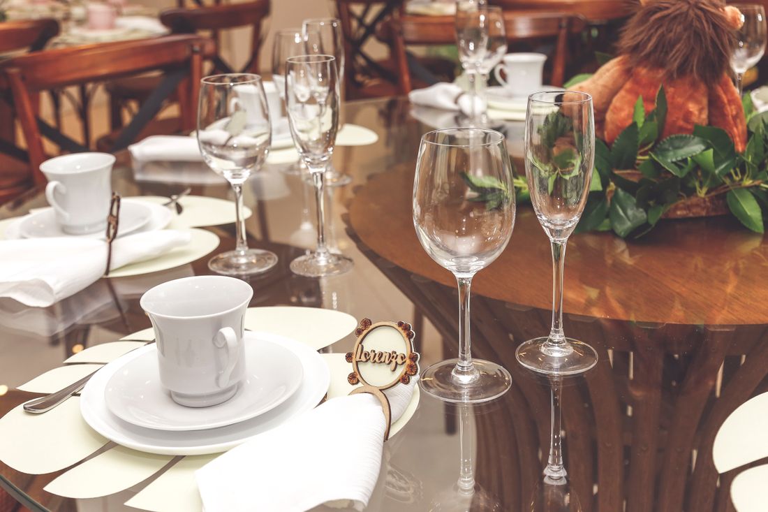 A place setting on a dressed table with wine glasses, plates, and a low centerpiece