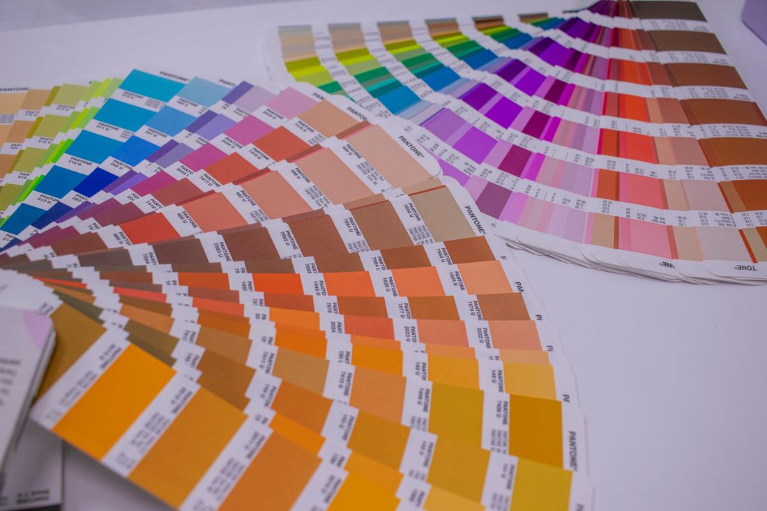 A fanned-out spread of printed color reference swatches showing a full rainbow of hues