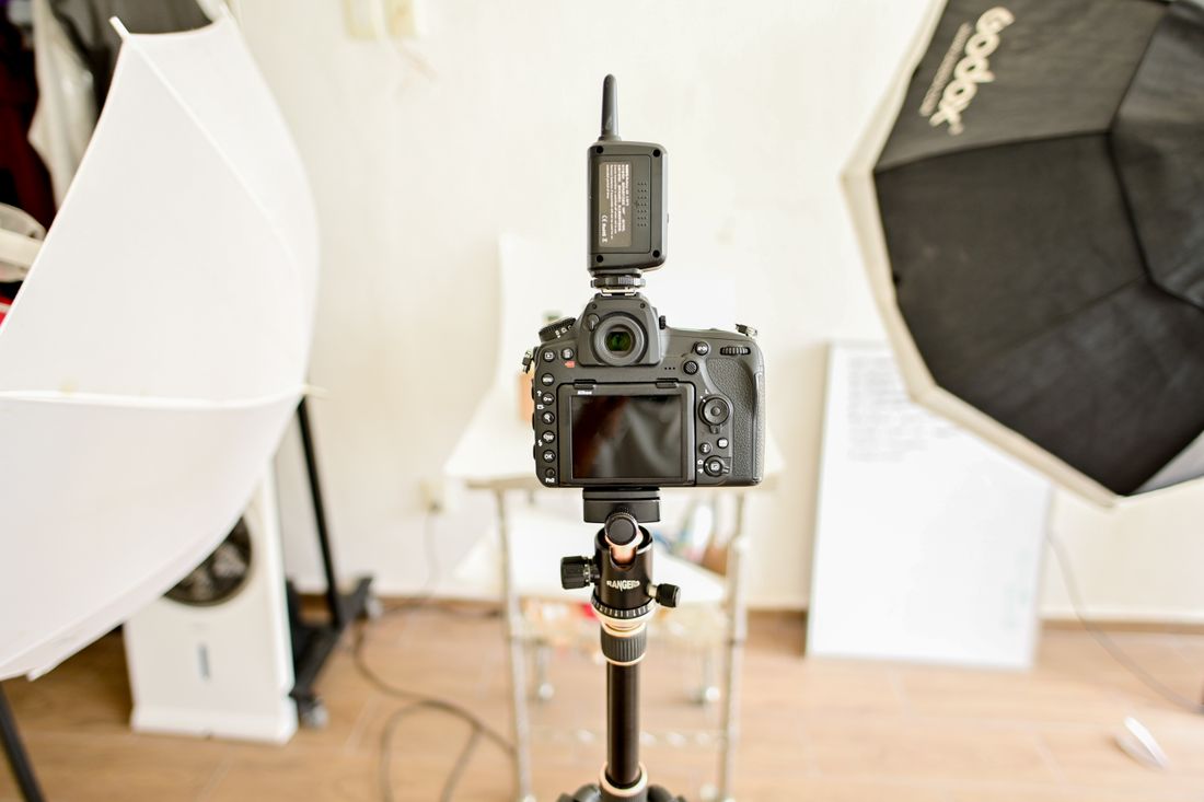 A professional DSLR camera mounted on a tripod with studio lighting equipment in the background