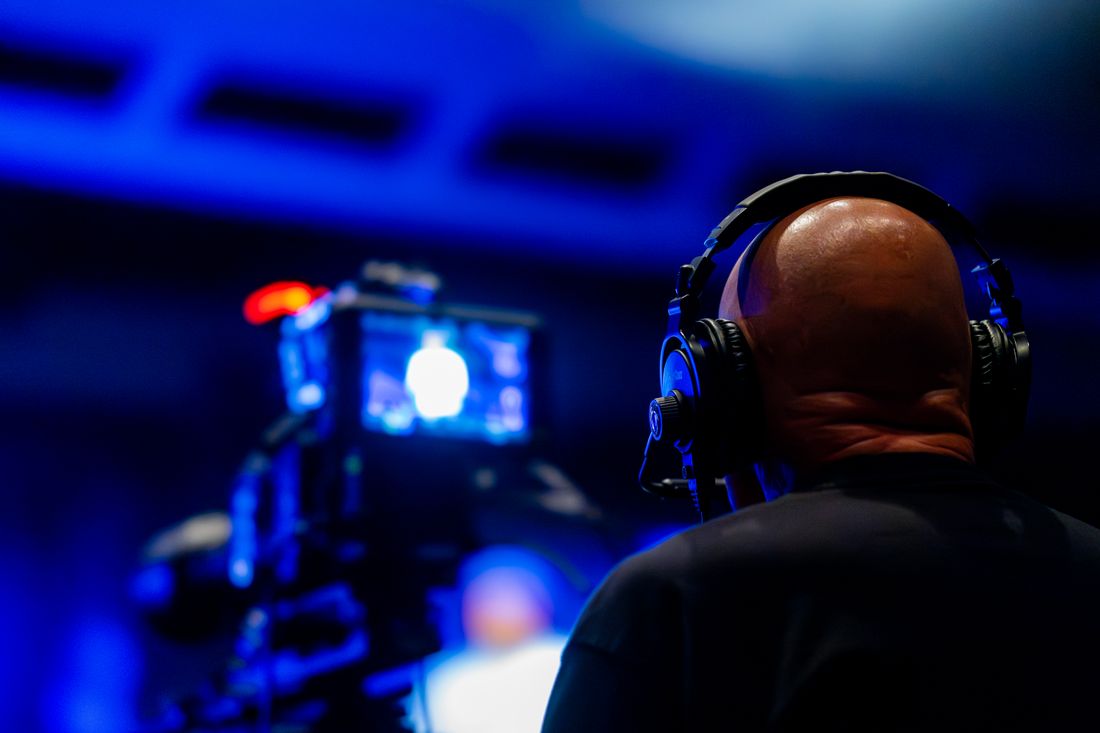 A videographer wearing headphones to monitor audio levels while filming an event