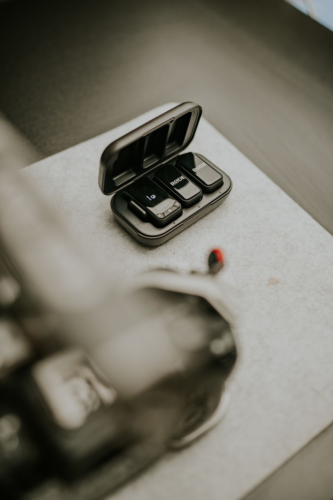 A wireless lavalier microphone set resting in its charging case on a desk
