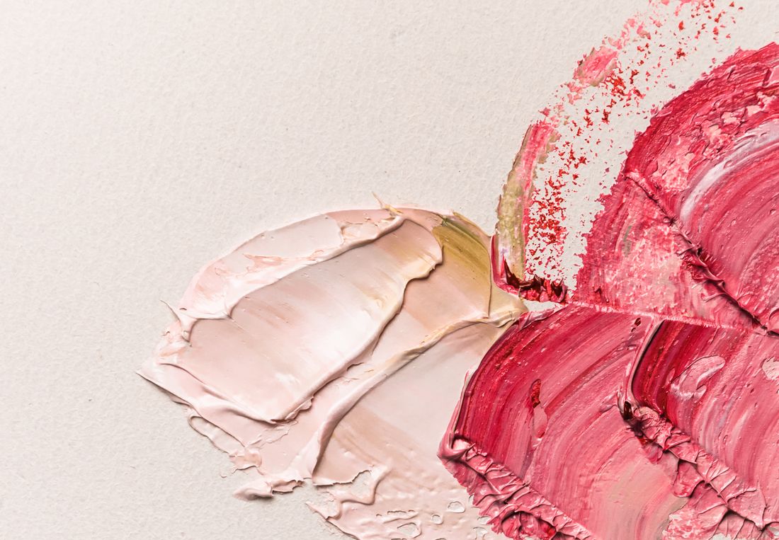 A close view of thick pink and red oil paint worked across a pale surface