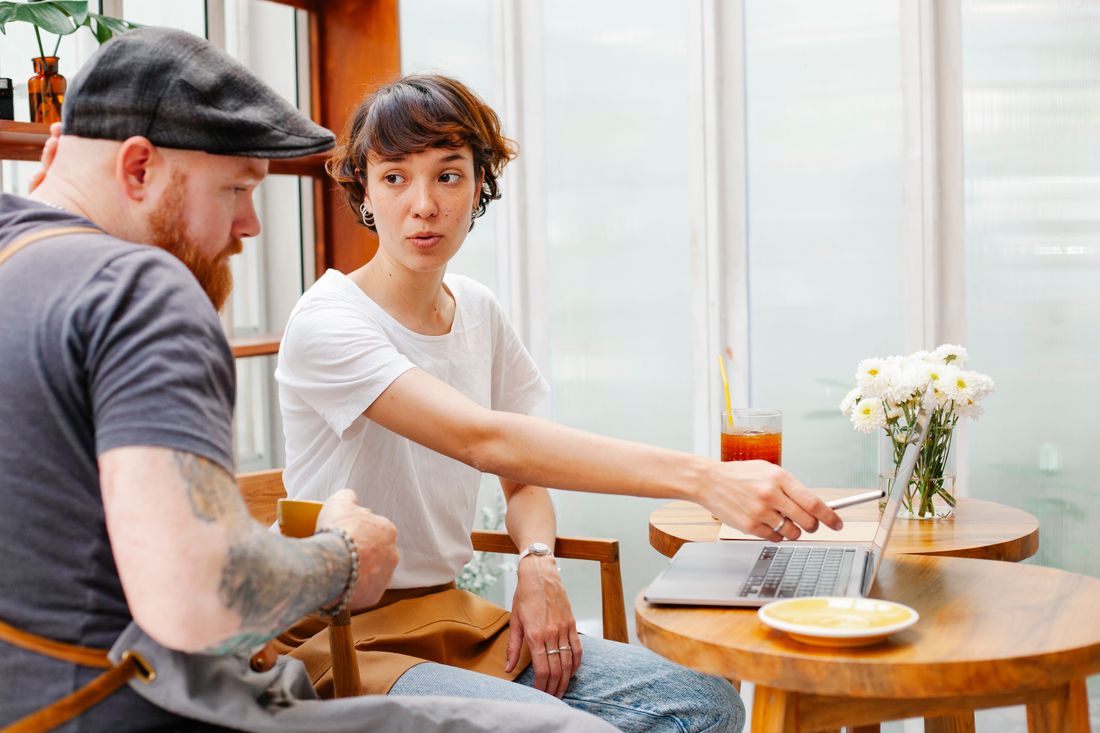 Two people looking together at a laptop screen indoors, mid-conversation