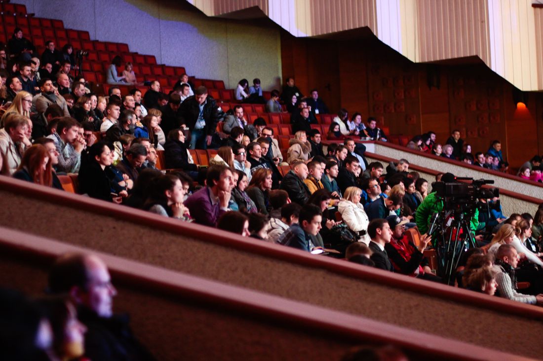 A full theater audience seated and listening during an indoor public program