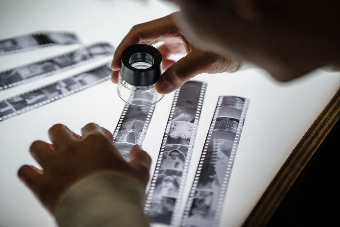 Hands examining a roll of film on a light table, reviewing frames closely