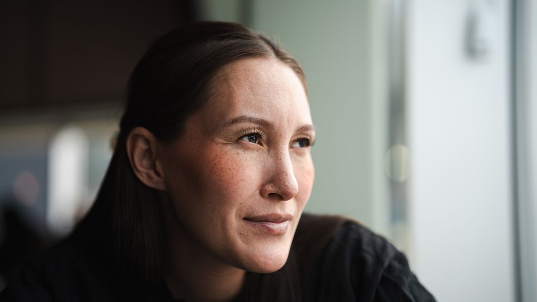 Woman in soft natural indoor light, looking away from the camera in a candid, unposed moment