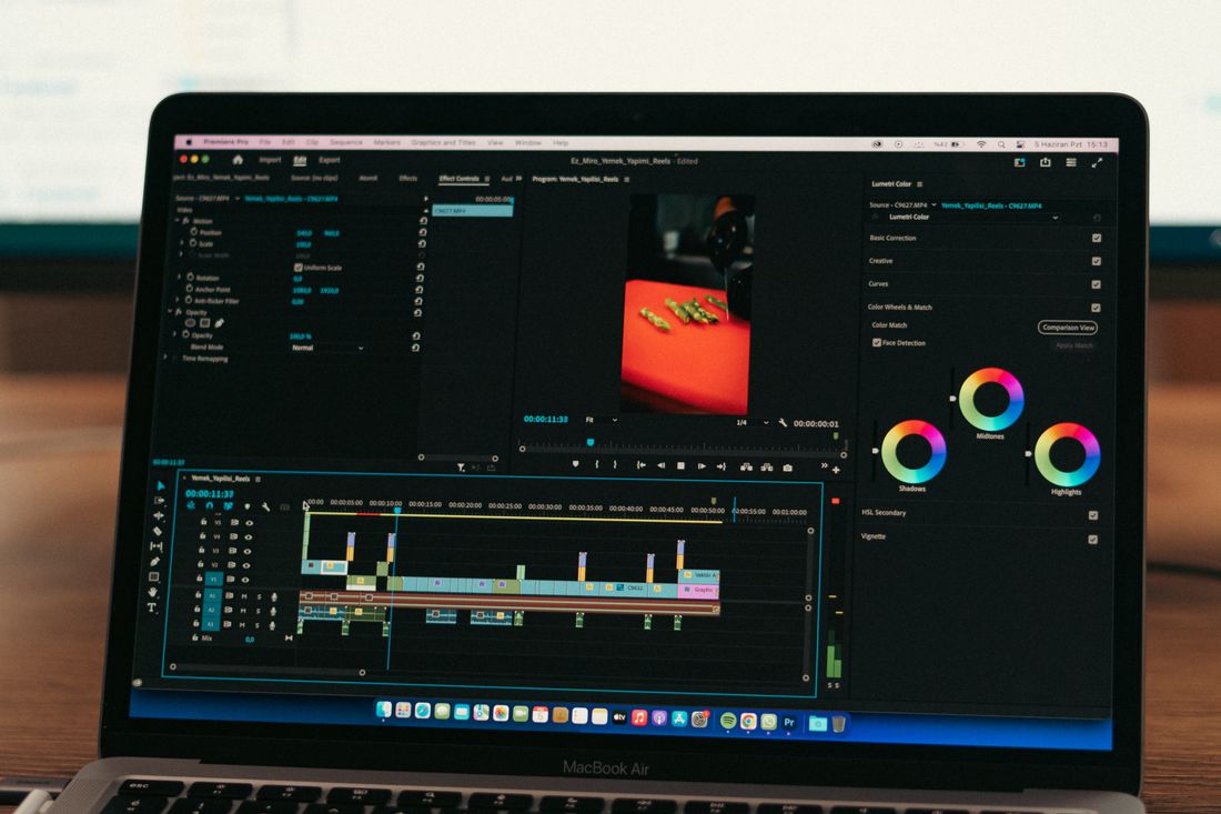 A laptop screen showing a video editing timeline with color-coded clips and a color grading panel