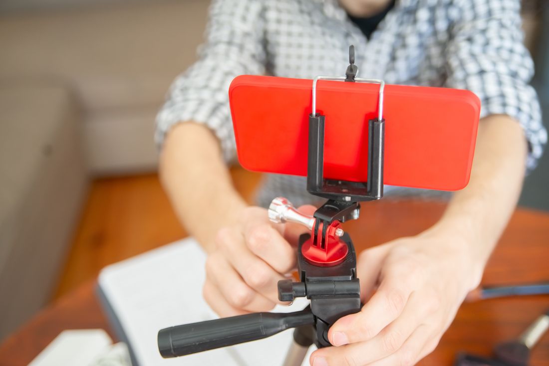 Close-up of hands mounting a smartphone onto a small tripod rig indoors