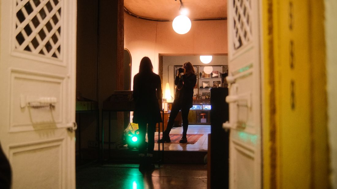 Silhouette of a photographer taking a portrait of someone in a dimly lit doorway