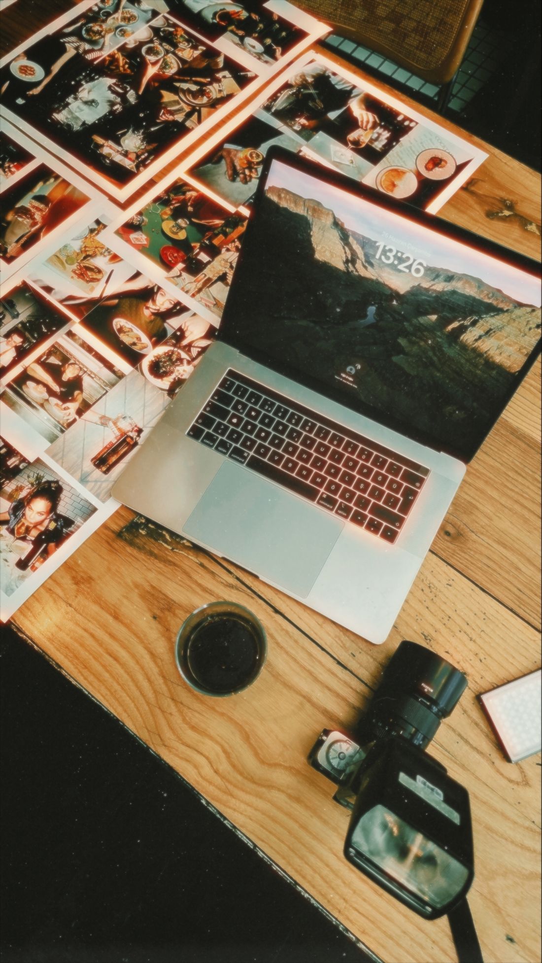 Laptop, camera, and lens laid out on a table in a creative workspace