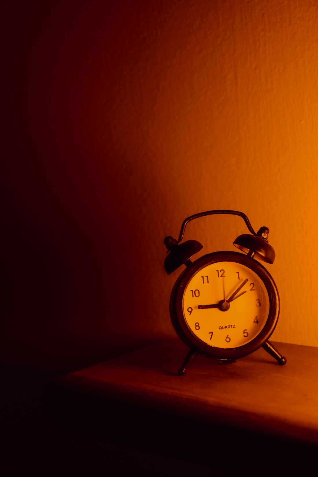 An analog alarm clock lit in warm, low evening light