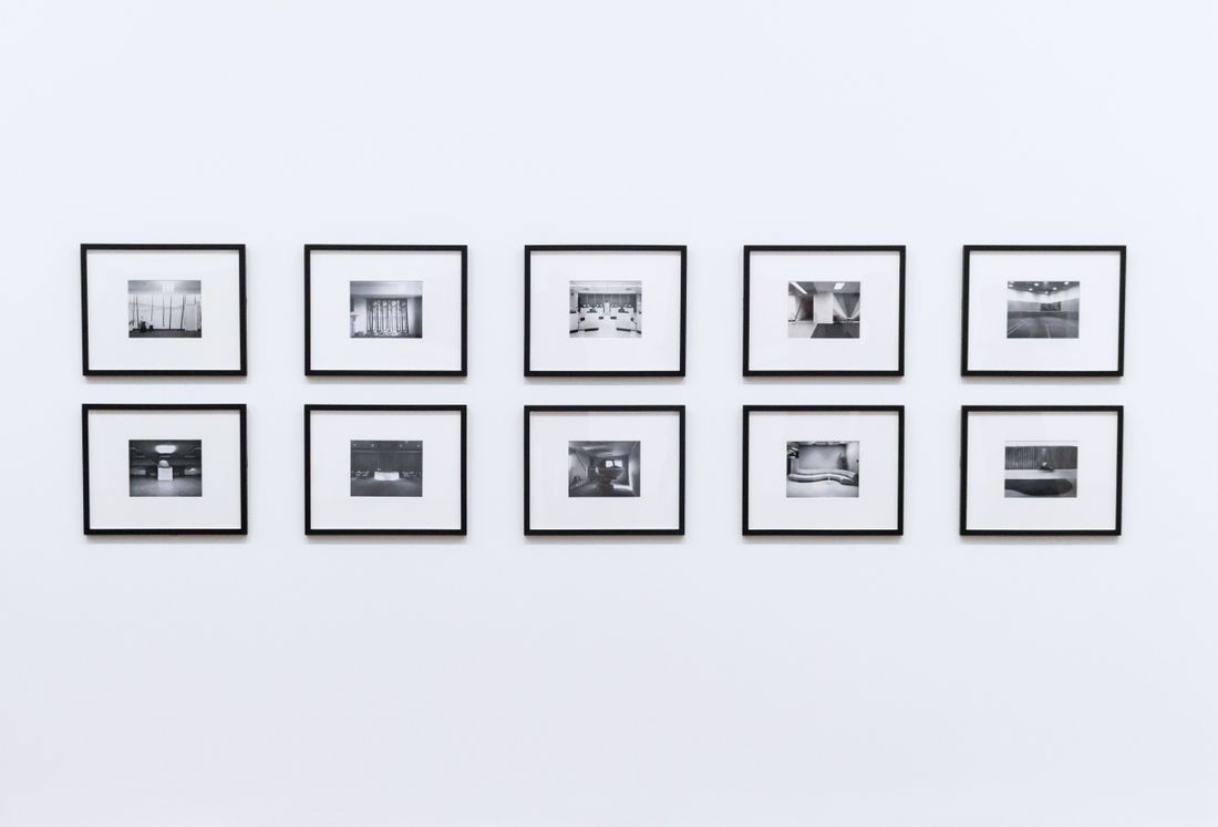 A clean grid of ten framed black-and-white photographs on a white gallery wall
