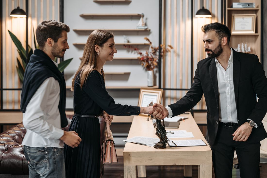 Two people shaking hands across a table during a consultation