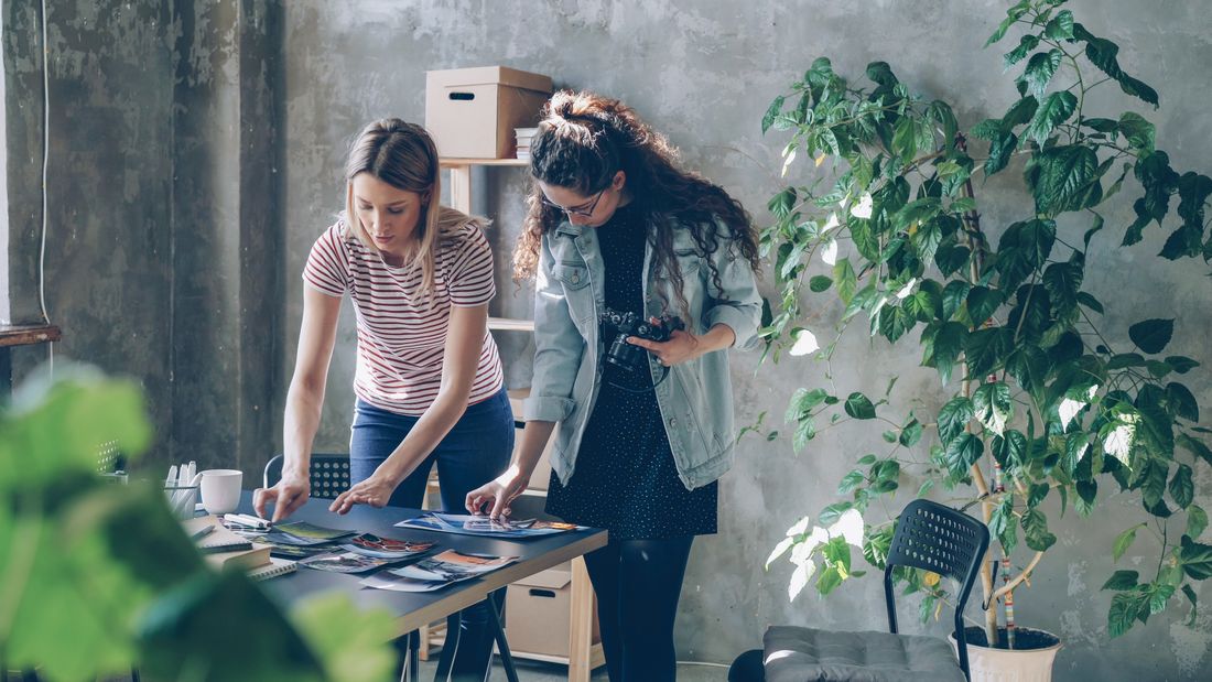 Two people reviewing a set of photography prints together at a table