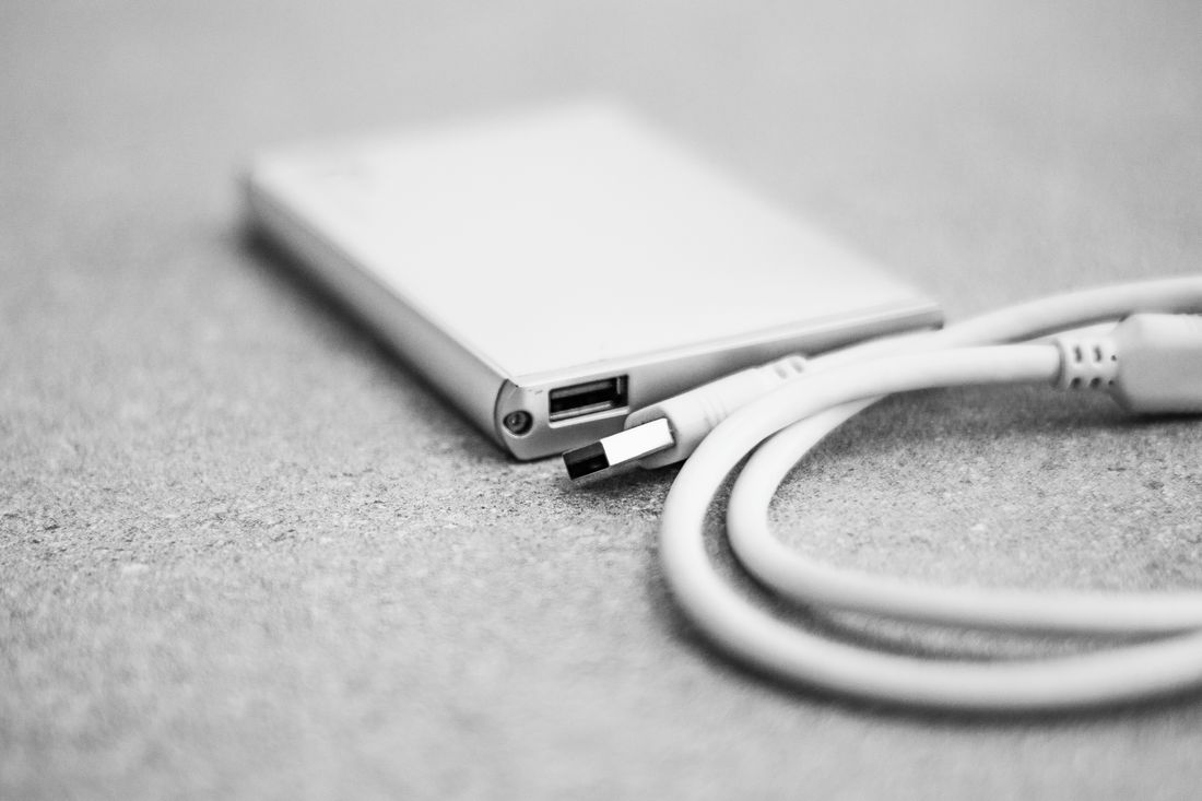 Close-up of an external hard drive and USB cable, isolated against a dark background