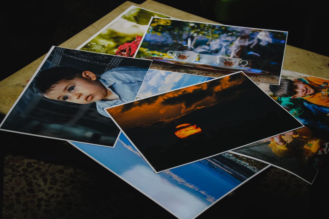 A collection of printed photographs spread out for review, various subjects and moods