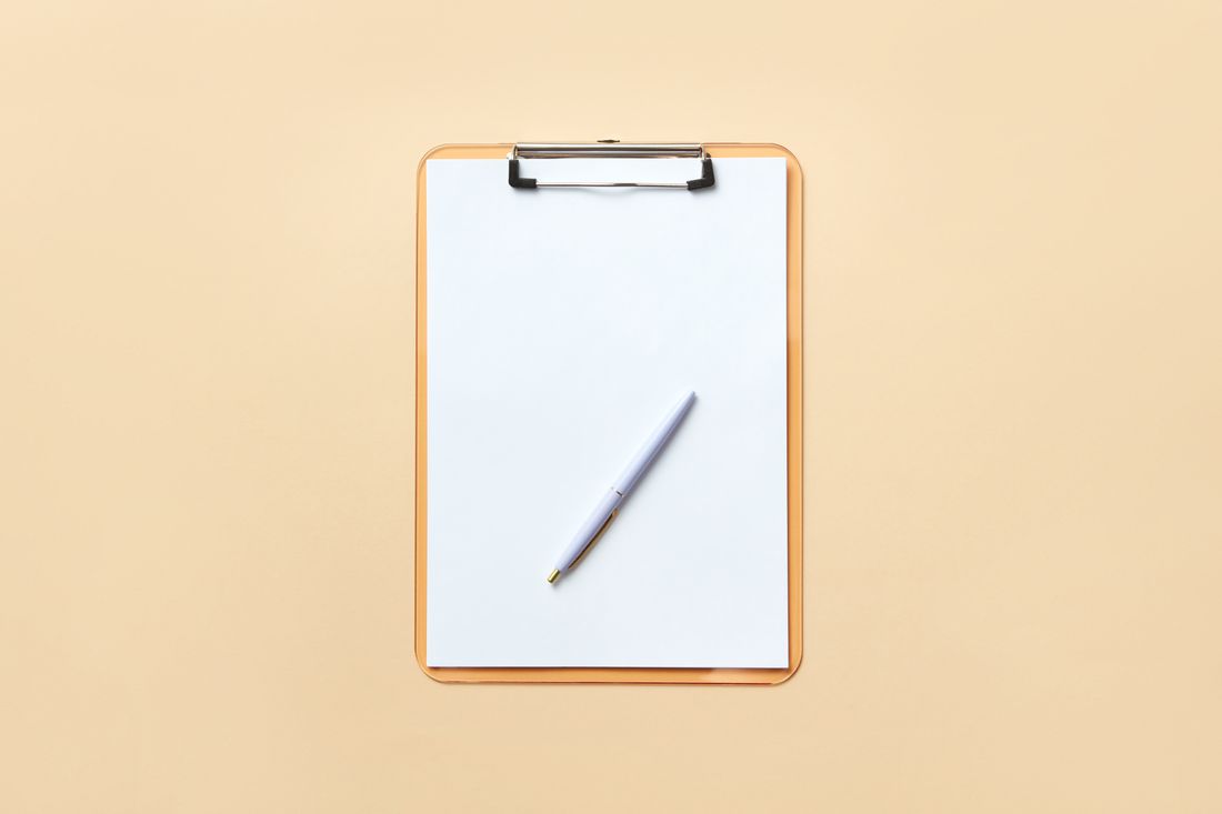 A blank clipboard holding an empty sheet of paper with a pen resting on top, photographed against a plain background.