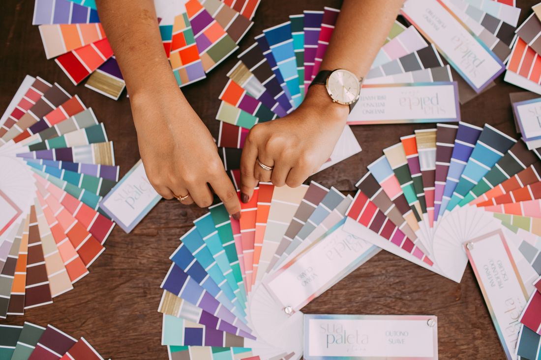 Hands sorting colorful fabric swatches spread across a table