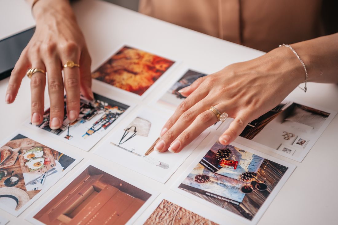 Two hands arranging printed photographs across a table during a planning review