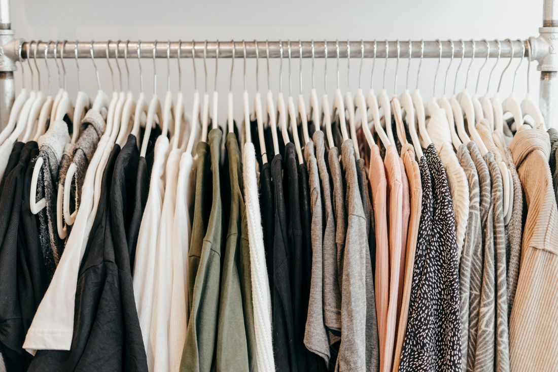 A close view of assorted clothing on hangers along a rack, showing a range of fabrics and colors
