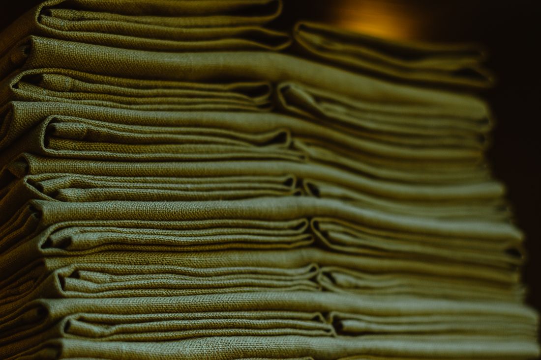 A close view of a stack of neatly folded fabric garments lying flat, warm ambient light
