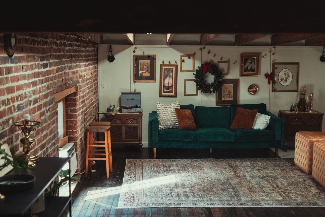 A row of framed paintings hung on the wall of a living room, with a sofa and furniture visible below
