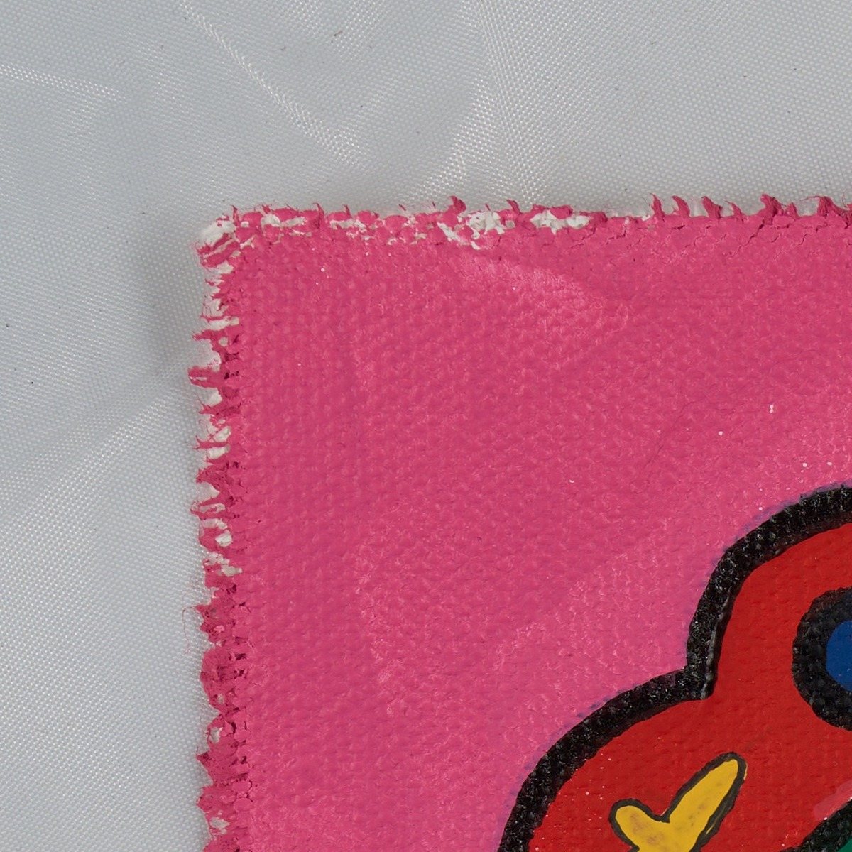 Full-size corner of the pink canvas, showing its frayed edge against a light backdrop